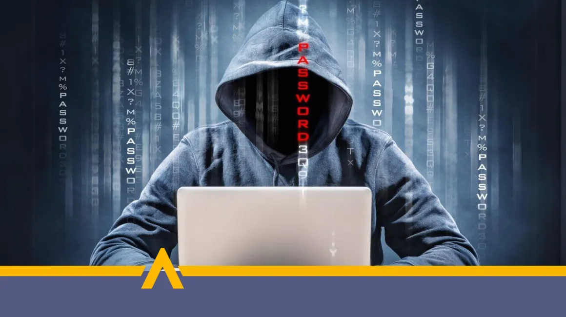 Haker w kapturze przy laptopie próbujący włamać się do systemu